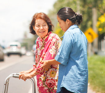caregiver assisting elderly woman in the road